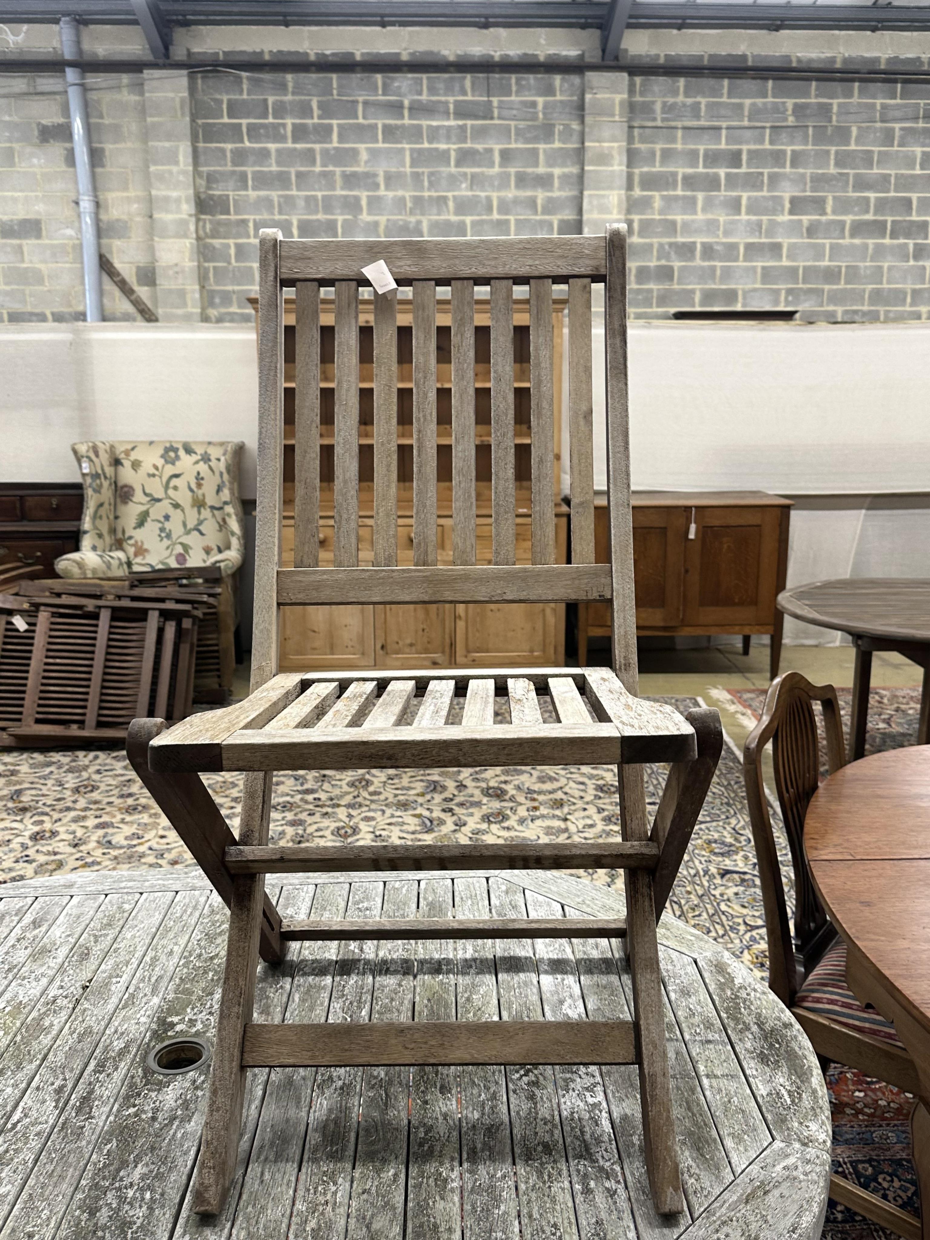 An oval weathered teak folding garden table, width 140cm, depth 100cm, height 76cm, together with six teak folding chairs, two with arms. Condition - fair